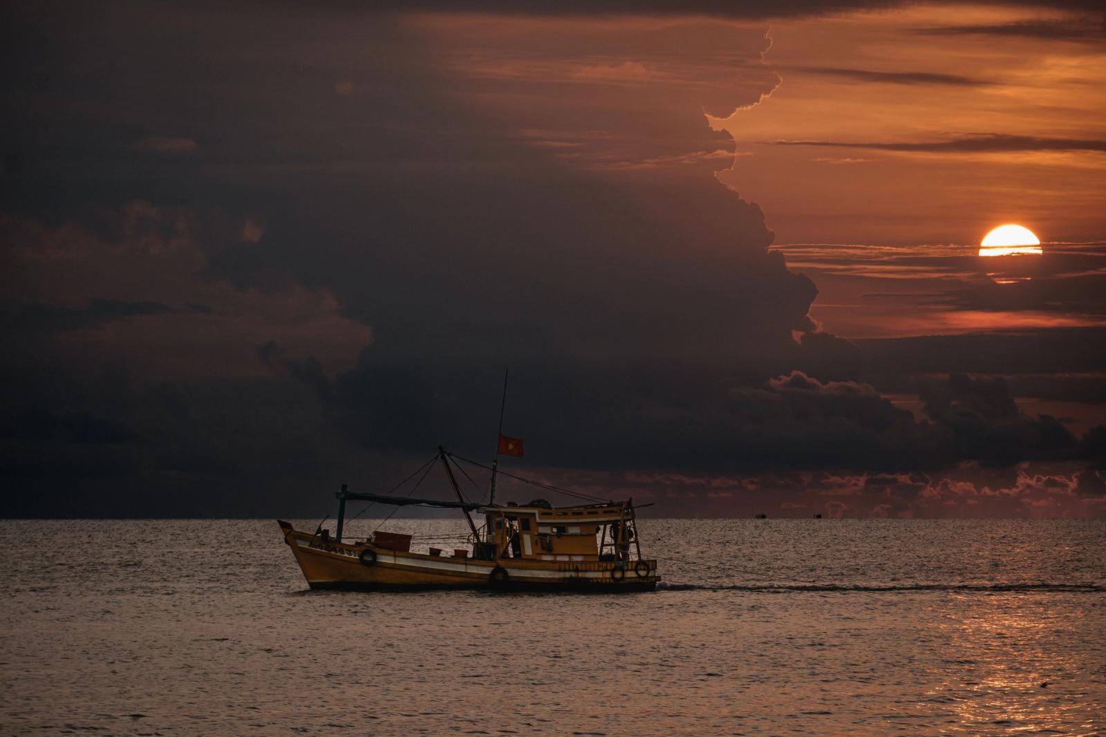 A fishing boat sails on the sea at sunset, captured in Phu Quoc, Vietnam