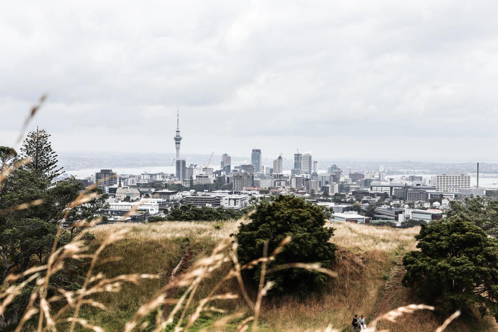 Distant view of Auckland's skyline from Mount Eden with sky tower under cloudy skies