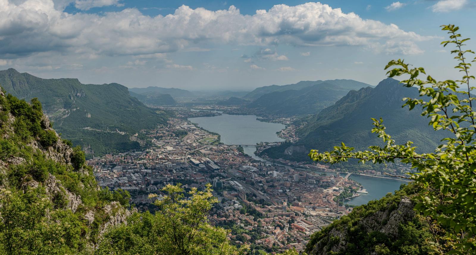 A breathtaking aerial view of Lecco surrounded by lush mountains and a serene lake in Lombardy, Italy