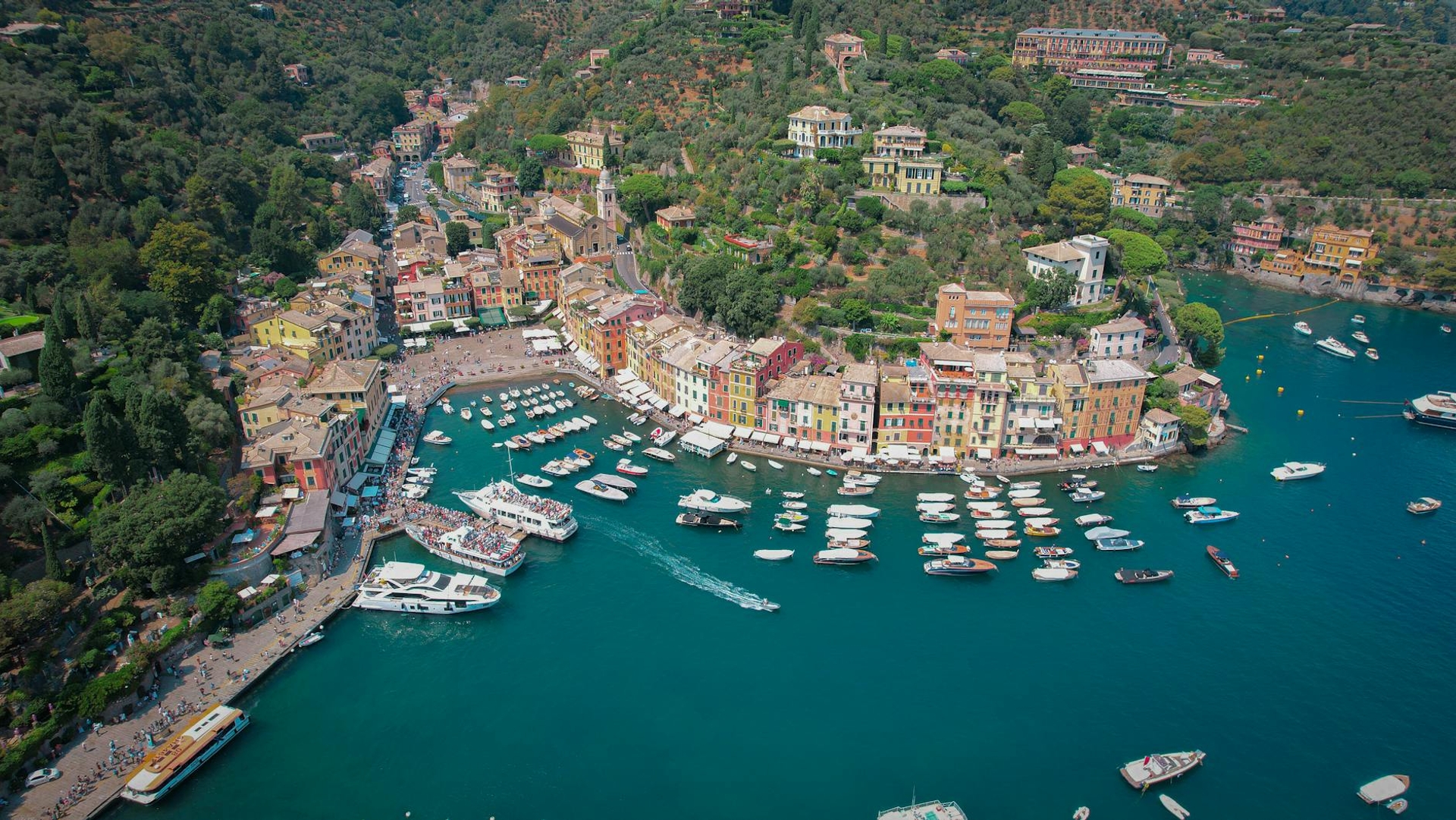 Aerial view of a colourful harbour town with boats moored in a bay