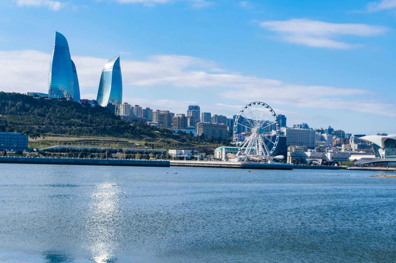 Twin flame-shaped skyscrapers rising above a harbourside ferris wheel