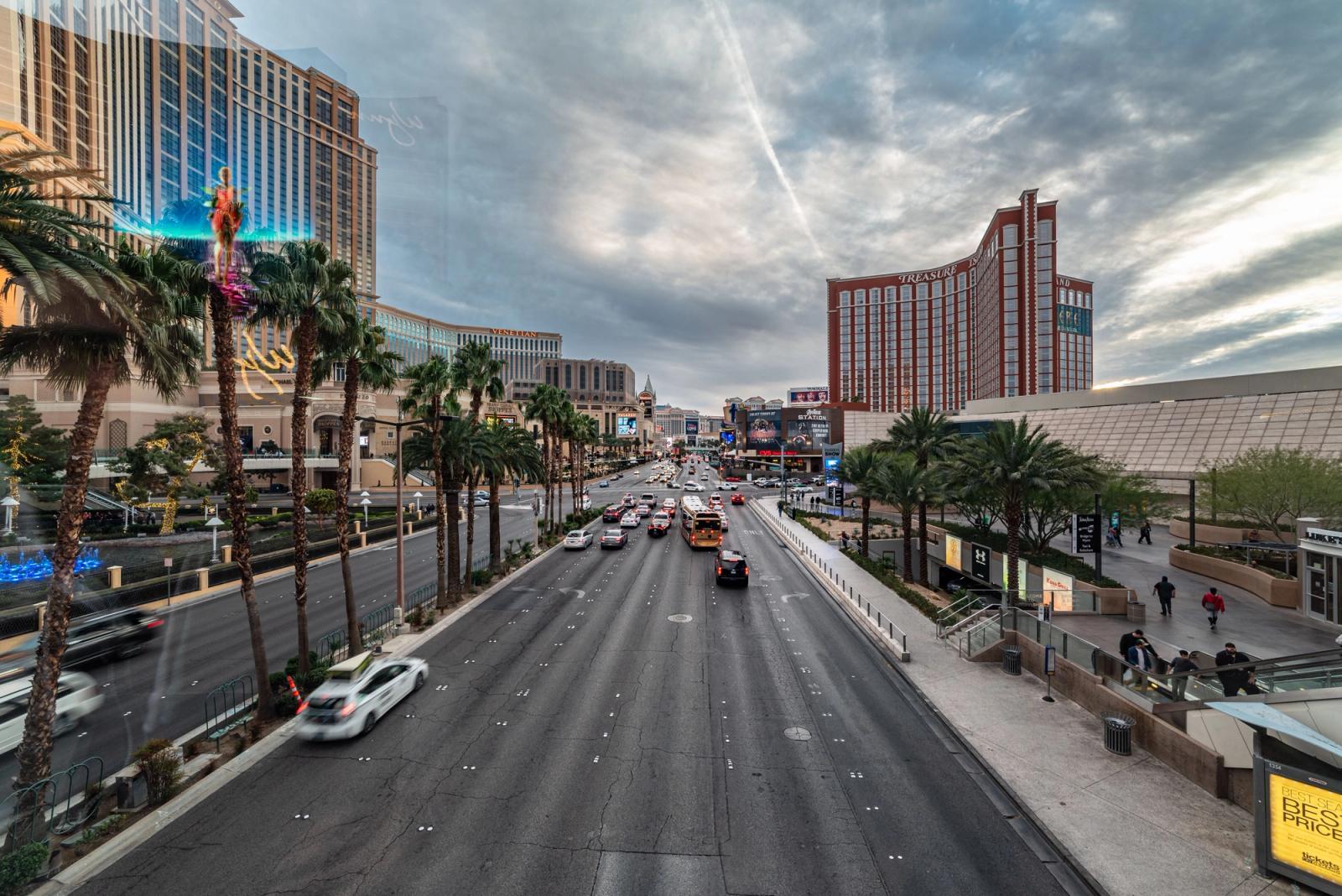 Dynamic view of the bustling Las Vegas Strip featuring traffic, palm trees, and vibrant architecture