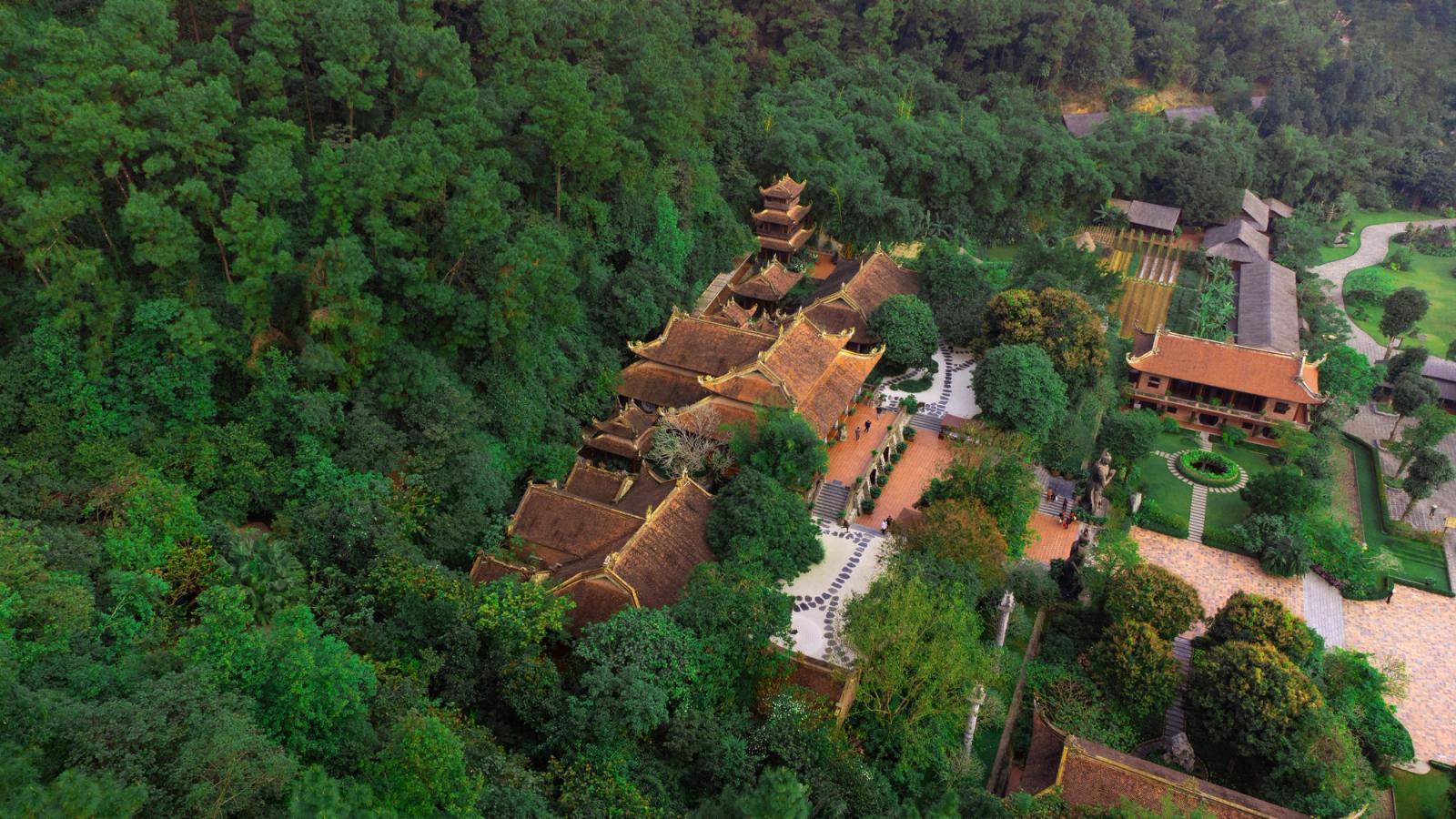 Aerial view of a traditional Vietnamese temple surrounded by lush greenery, capturing the serene atmosphere and architectural harmony