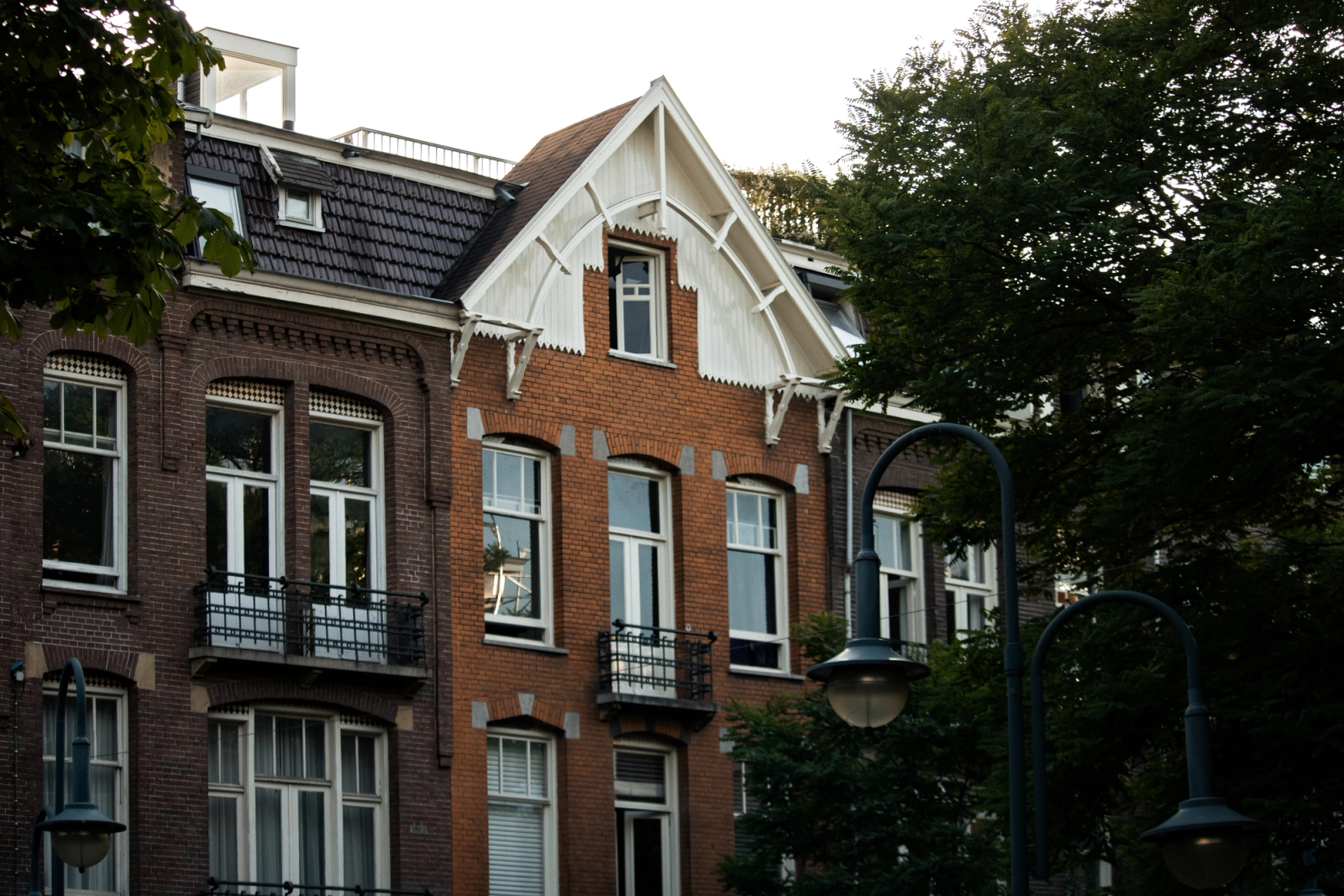 Vintage-style brick building in Amsterdam surrounded by trees, showcasing classic architecture