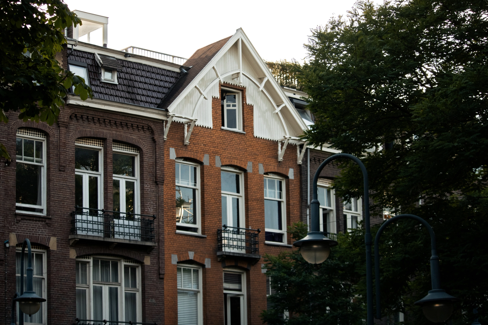 Vintage-style brick building in Amsterdam surrounded by trees, showcasing classic architecture