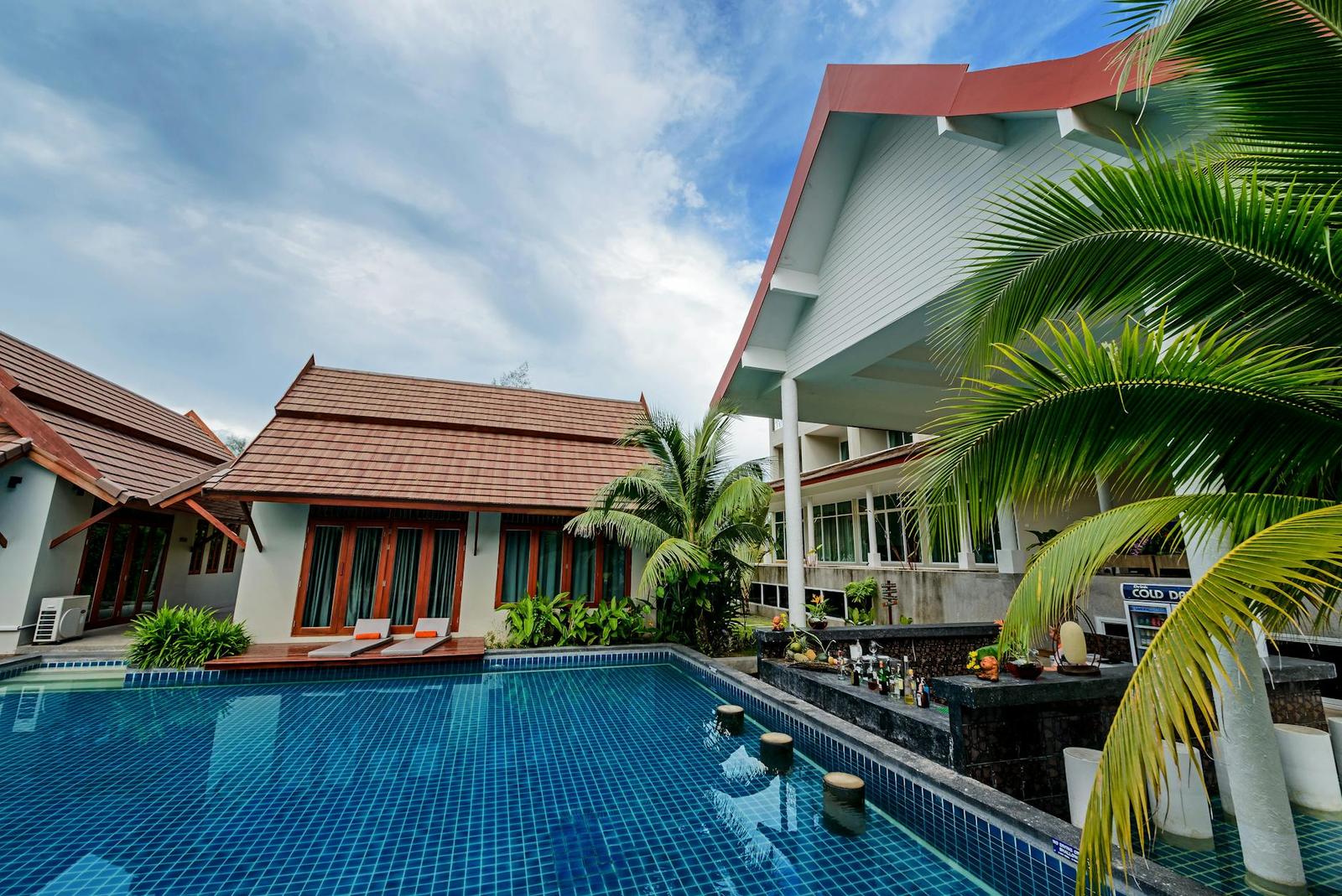 Poolside villas with red-tiled roofs and palm trees around a swimming pool