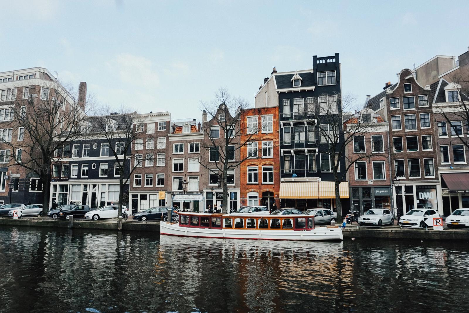 A tour boat passing gabled canal houses on a city waterway