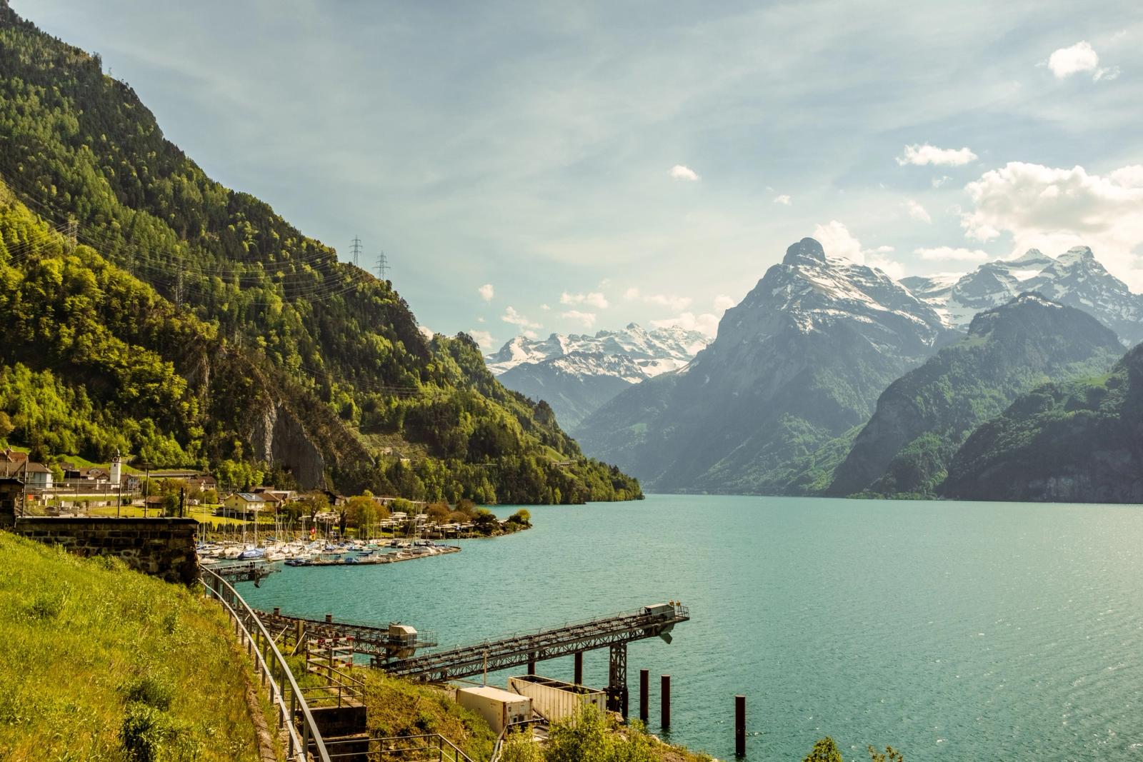 Panoramic view of scenic mountains and tranquil lake in Switzerland under bright afternoon sky