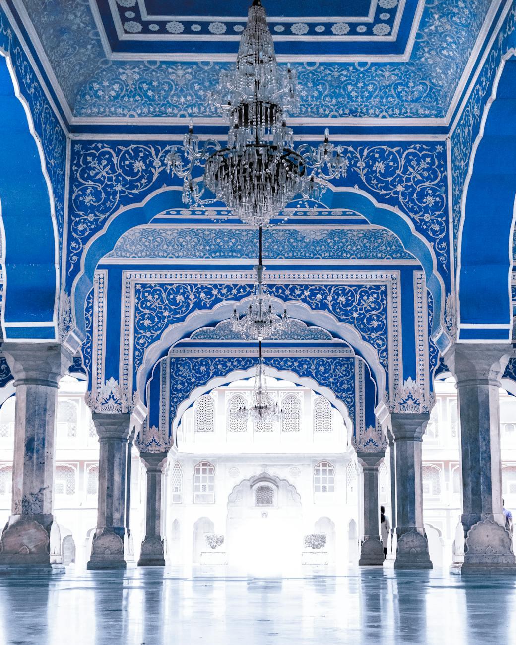 Ornate blue and white mirrored hall with a crystal chandelier and arched doorways