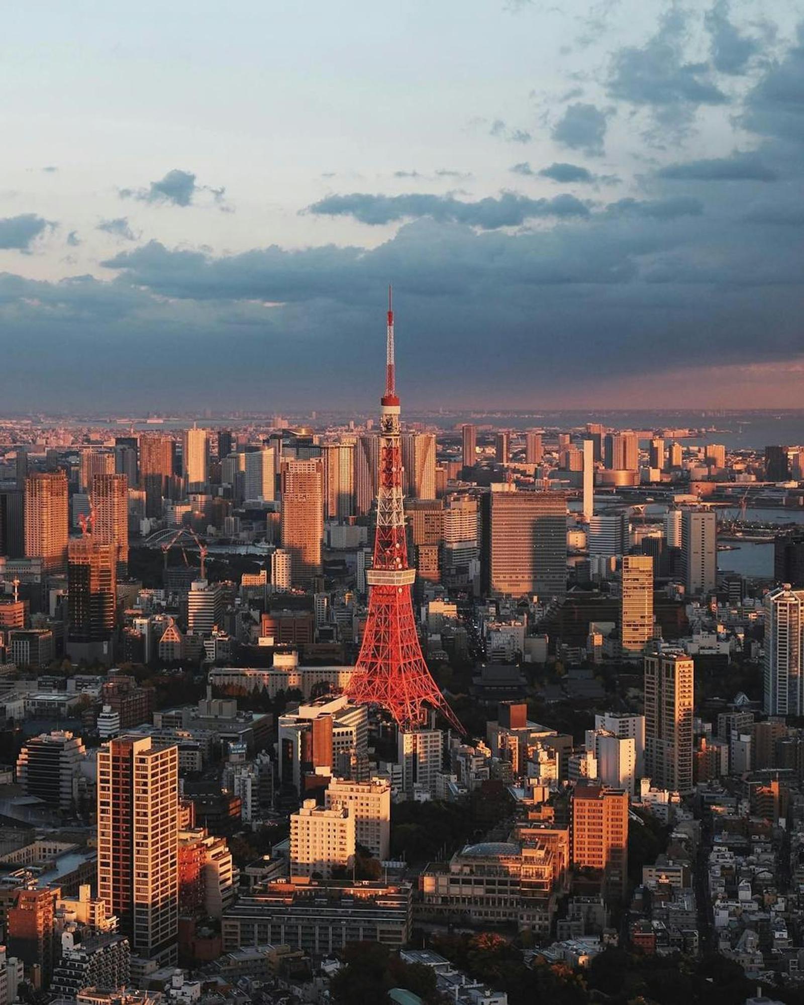 Aerial view of Tokyo Tower glowing red among skyscrapers at dusk