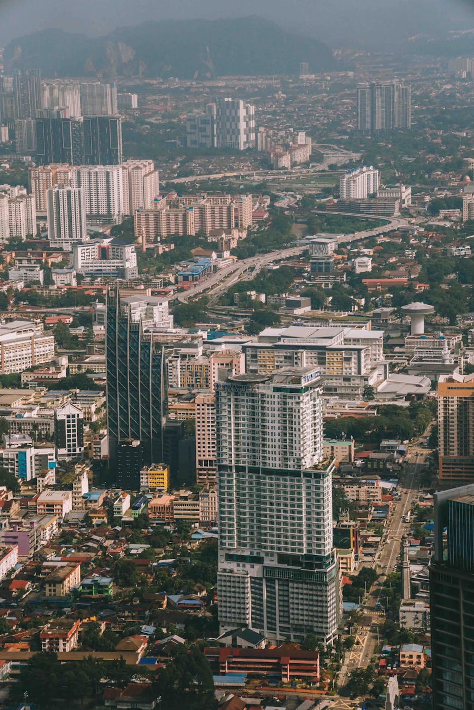 Aerial cityscape of high-rise apartment towers stretching toward distant hills