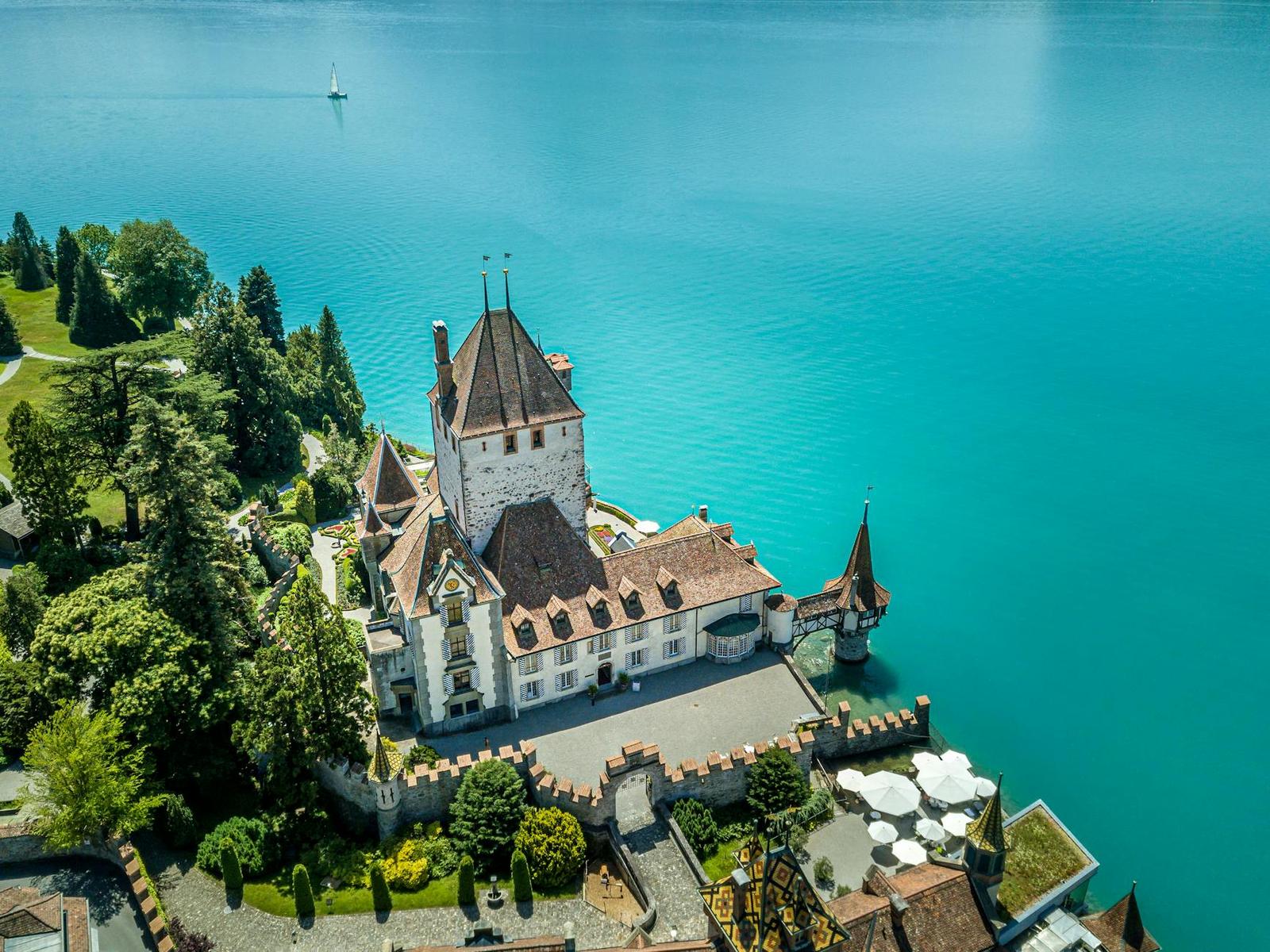 Turreted lakeside castle on a peninsula surrounded by turquoise water