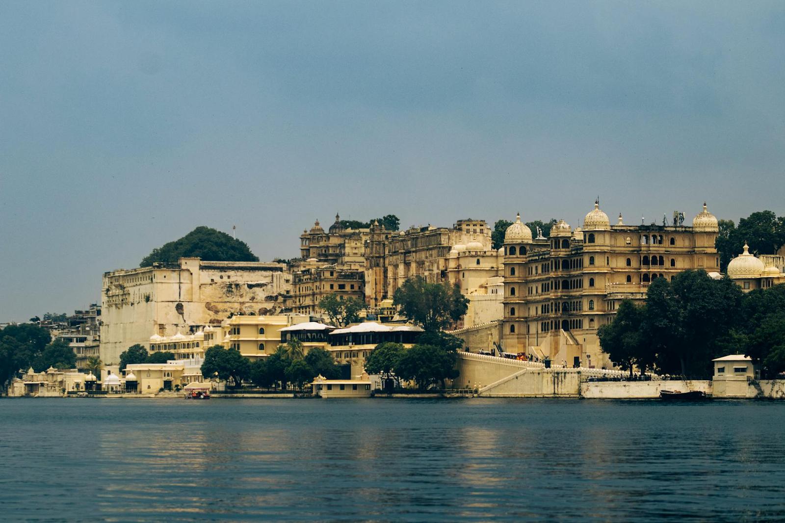 A sprawling lakeside palace complex with domed towers reflected in still water