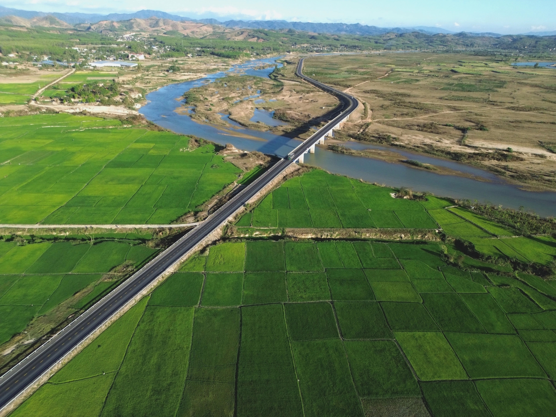 Aerial view of green rice fields, river, and bridge in Kon Tum, Vietnam