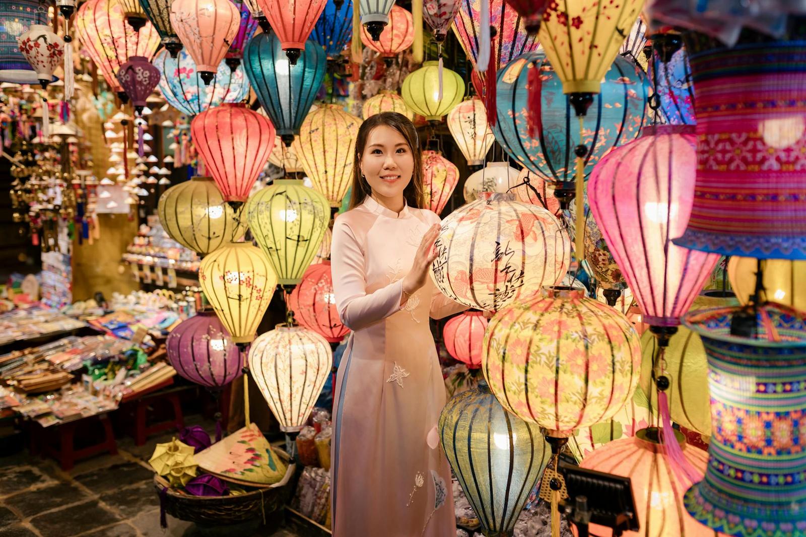 A woman in traditional Ao Dai surrounded by vibrant lanterns at a market in Hội