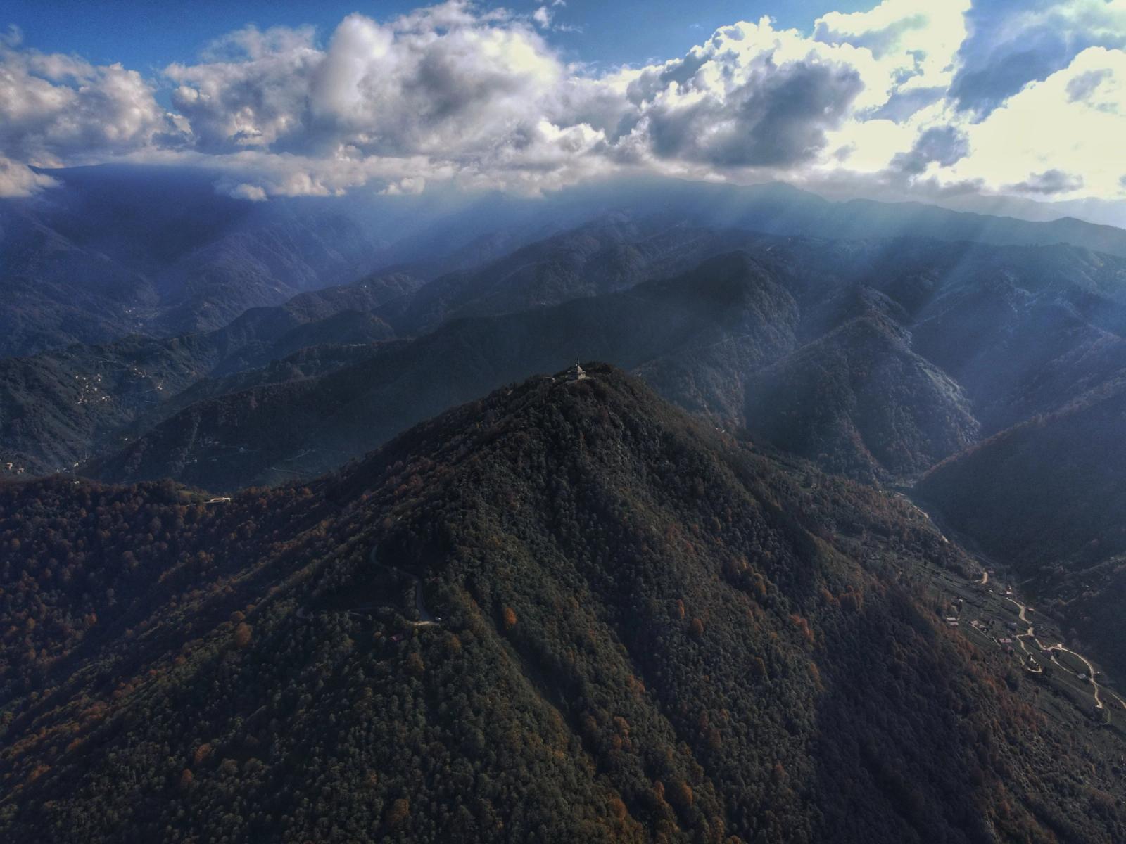A breathtaking aerial view of a mountainous landscape with sunbeams piercing through clouds