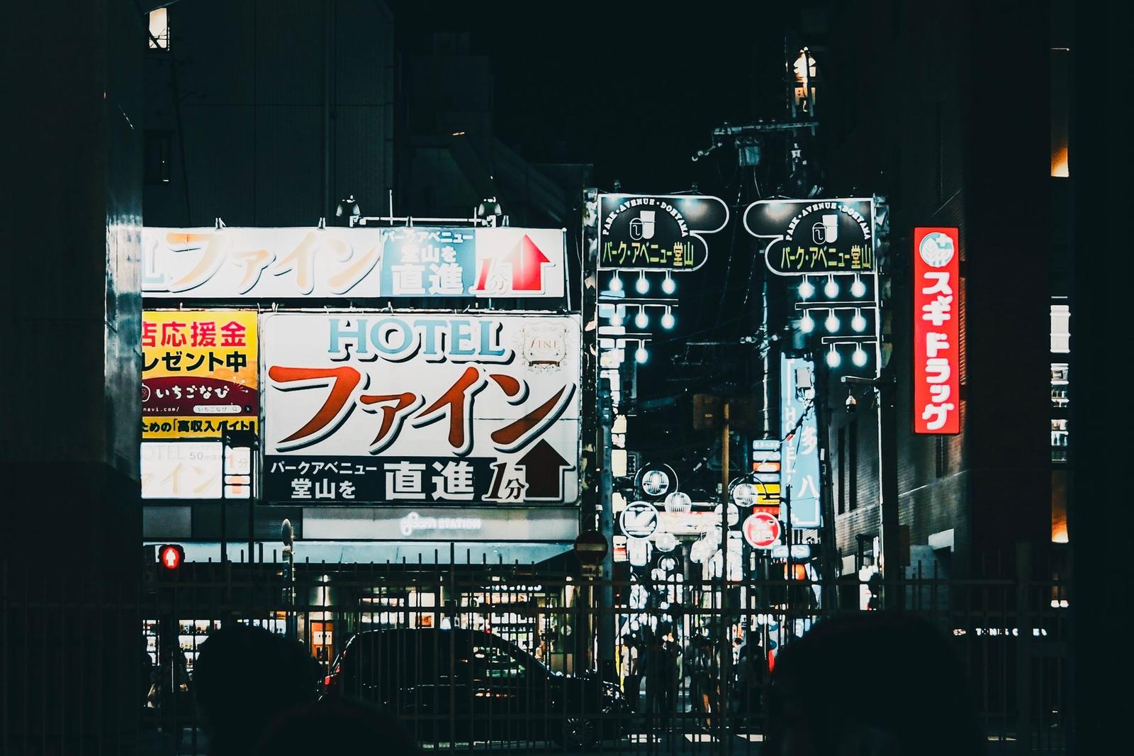 Illuminated neon signs including a hotel sign on a night city street