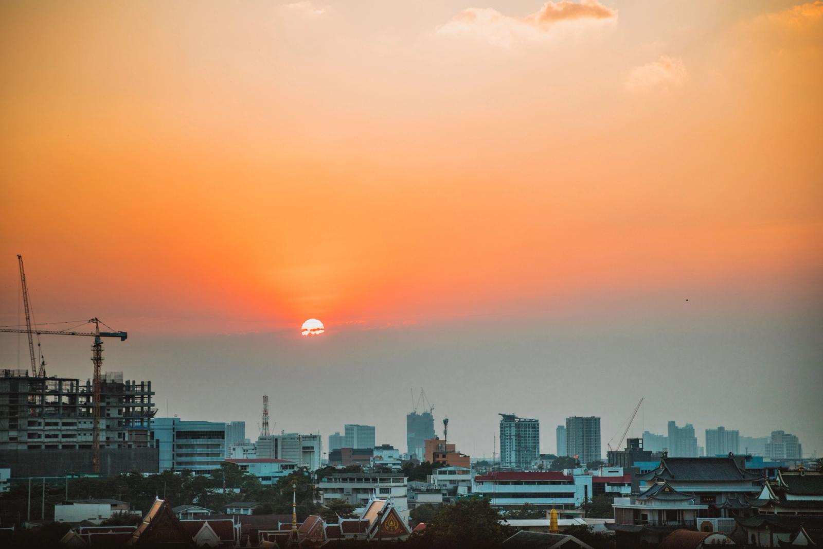 Stunning Bangkok skyline with cranes and a warm sunset over the city