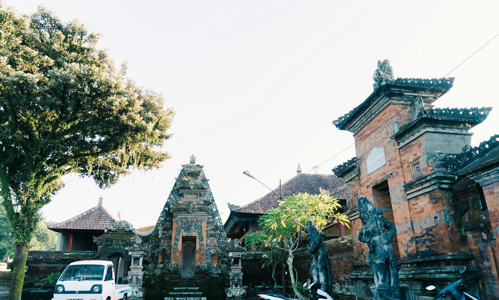 A serene view of a traditional Balinese temple surrounded by trees and architectural elements