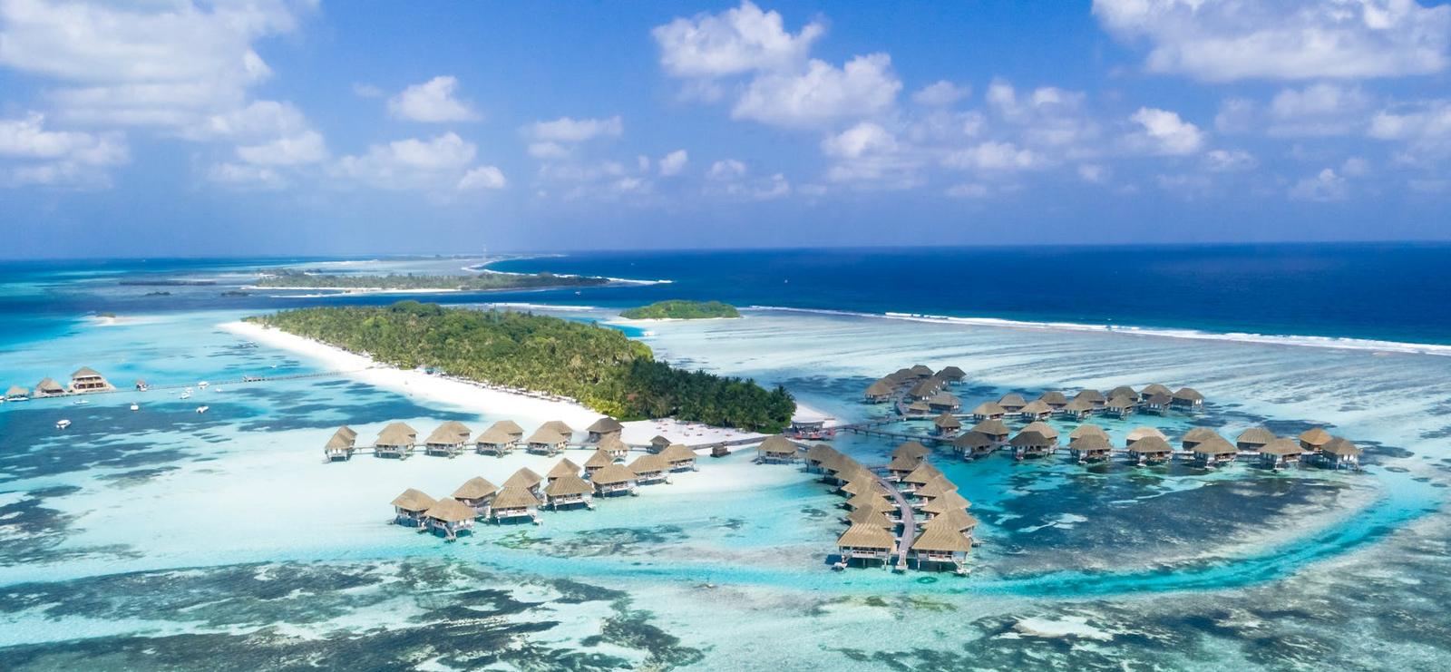 Aerial view of a resort with thatched overwater villas on a reef