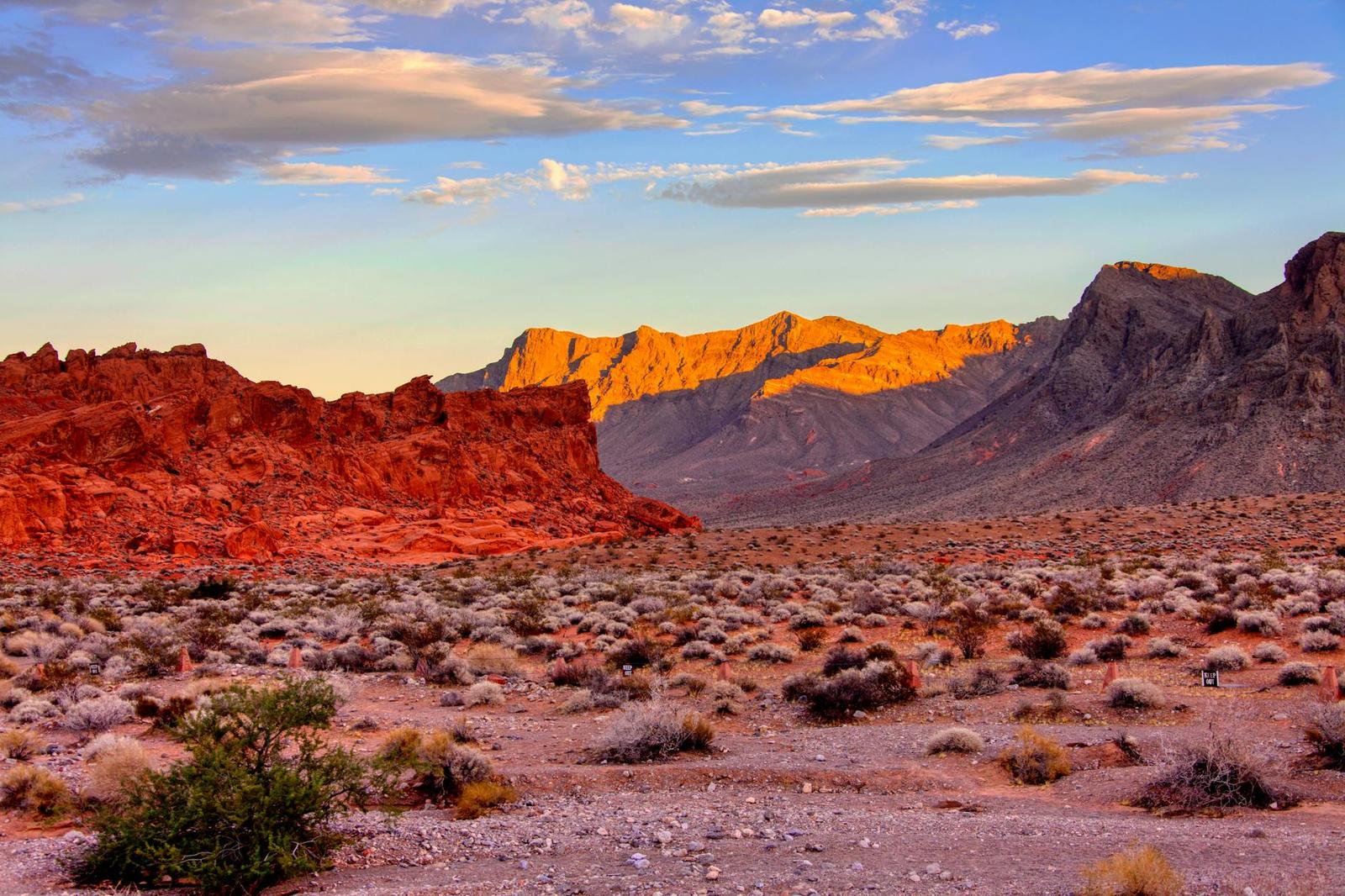 Red rock outcrop glowing at sunset above a desert scrubland
