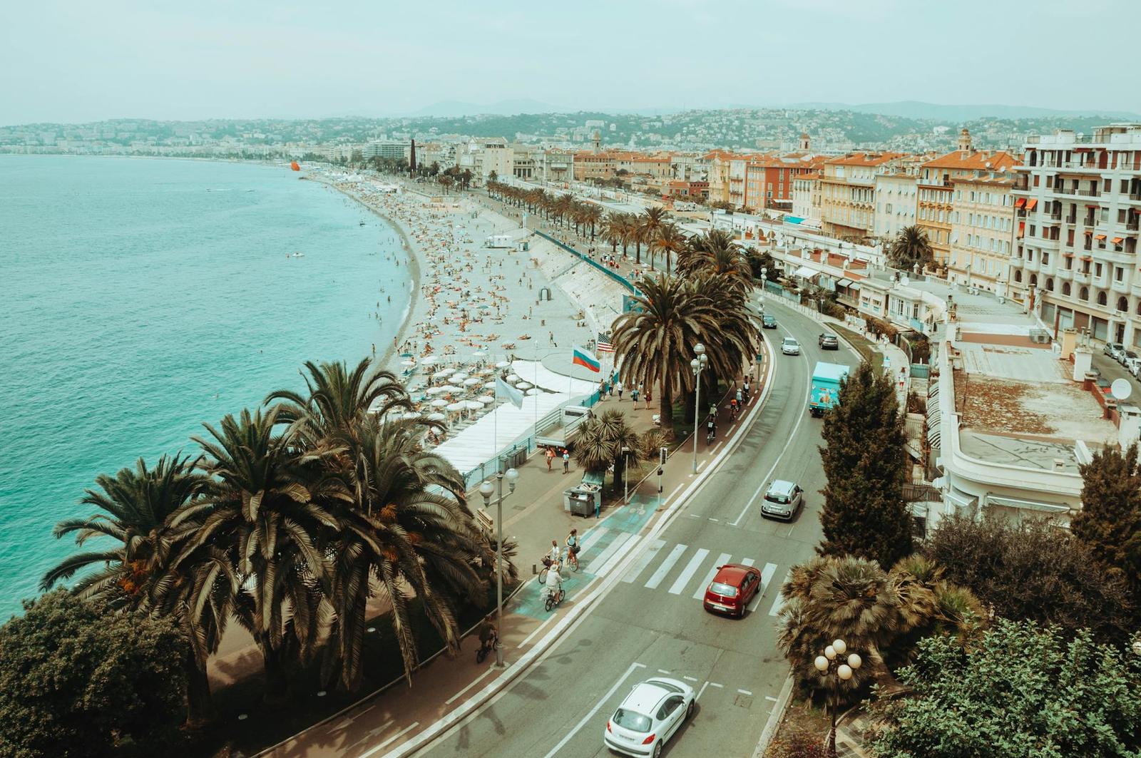 Aerial view of a palm-lined seaside promenade and crowded beach