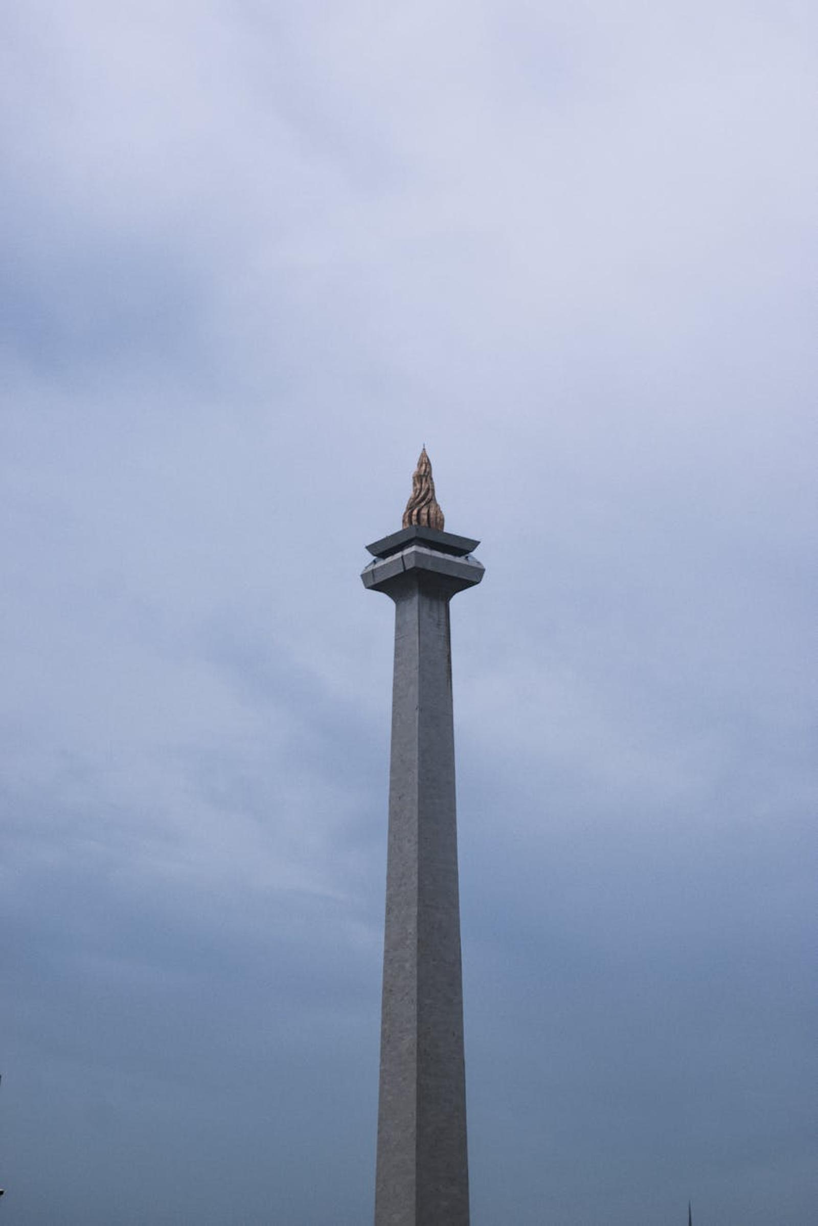 The National Monument in Jakarta stands tall under a cloudy sky
