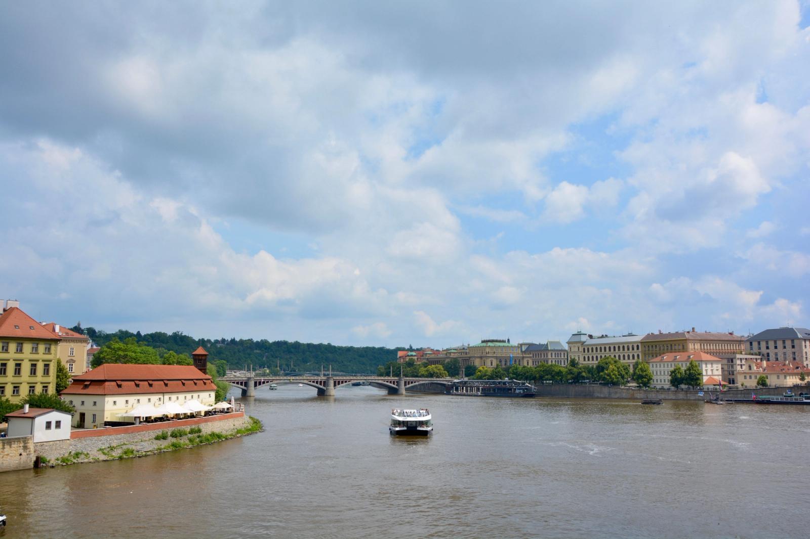 A serene day on the Vltava River in Prague surrounded by historic architecture and lush greenery