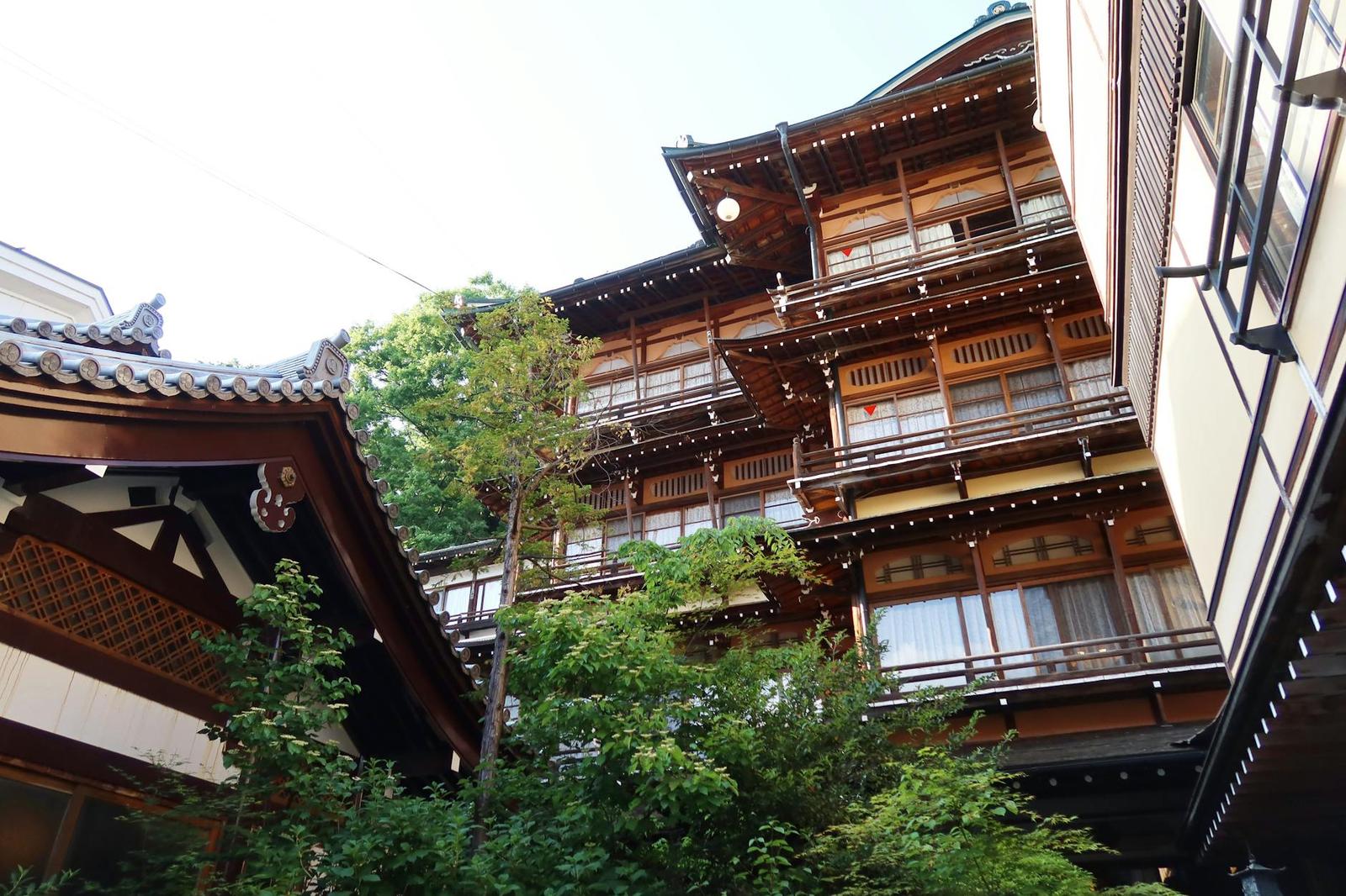 A multi-storey wooden ryokan building tucked among trees