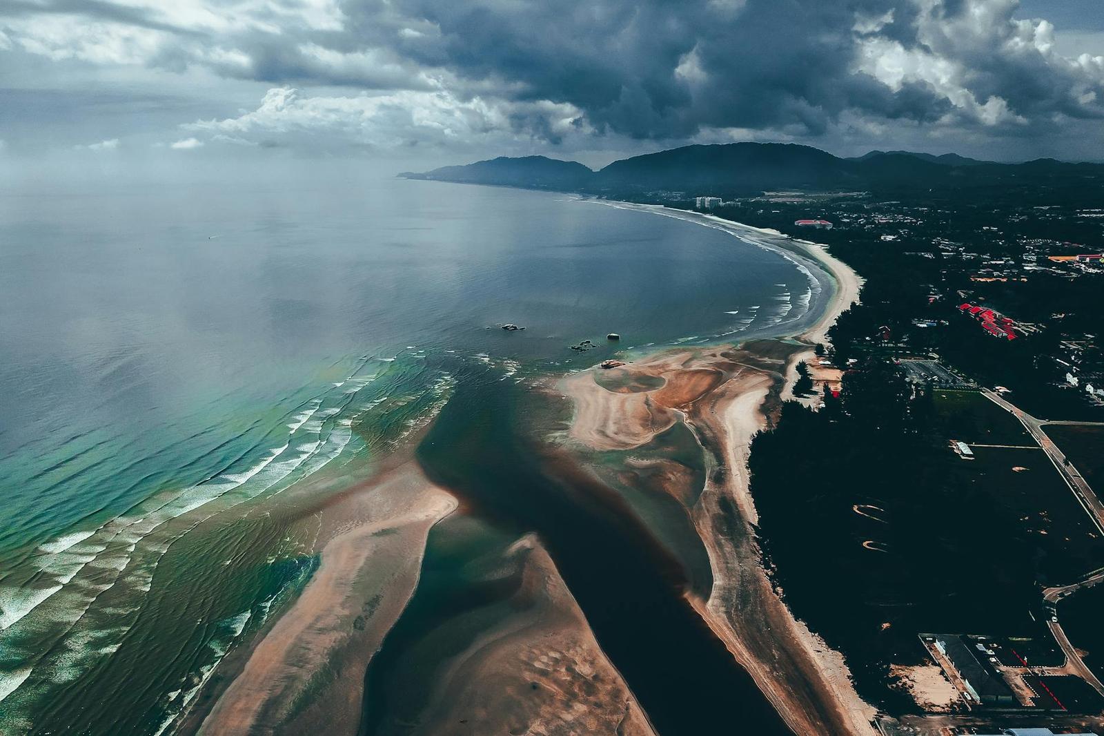 Aerial view of a river delta meeting a curving sandy coastline