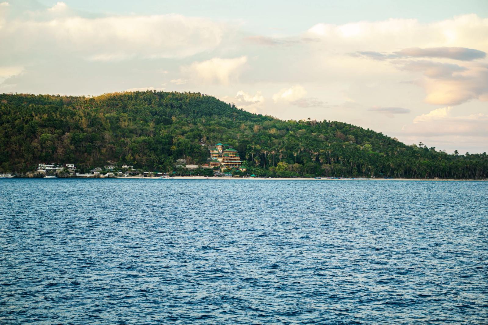 A beautiful coastal landscape featuring lush green hills and a serene ocean under a partly cloudy sky