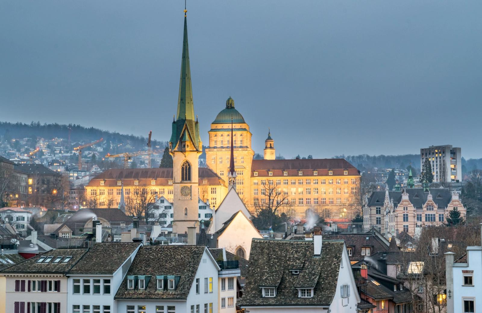A stunning aerial view of Zurich showcasing the iconic Predigerkirche and urban landscape at twilight