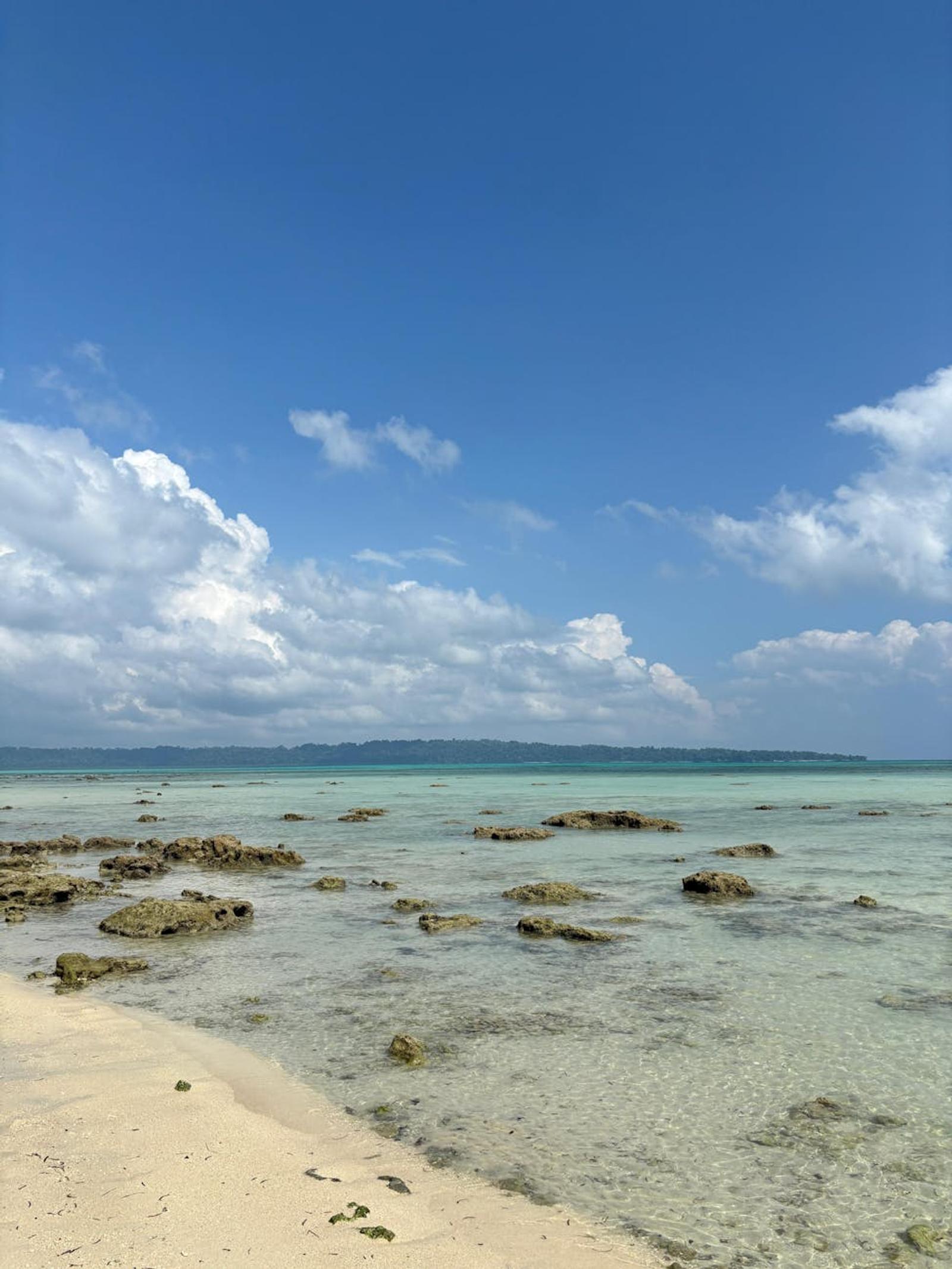 Clear shallow water over a rocky shoreline meeting a sandy beach