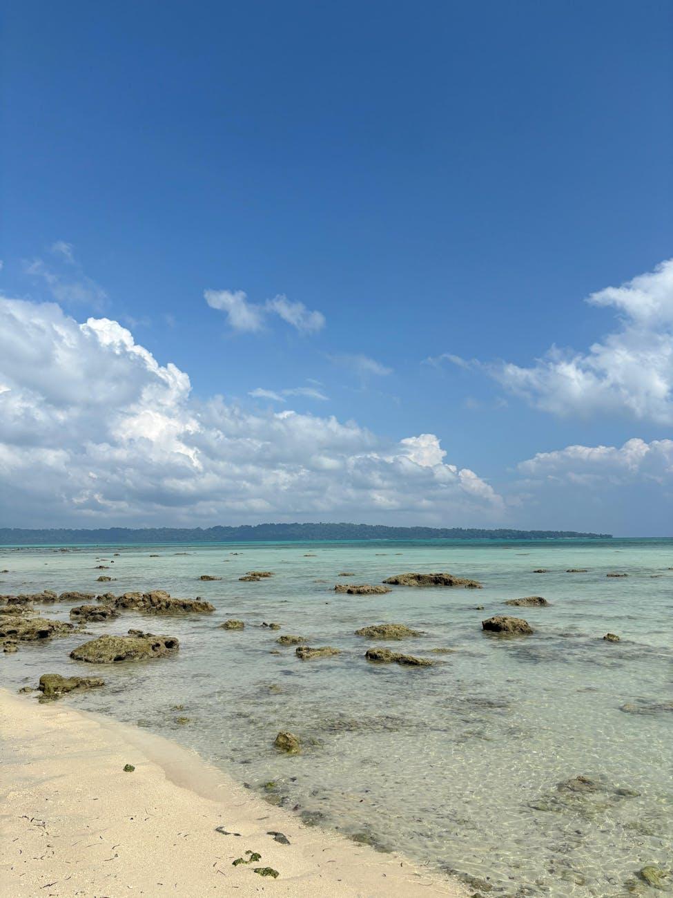 Clear shallow water over a rocky shoreline meeting a sandy beach