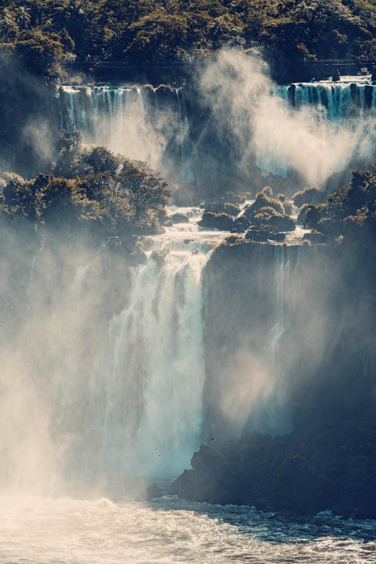 Multiple waterfalls cascading through misty rainforest cliffs