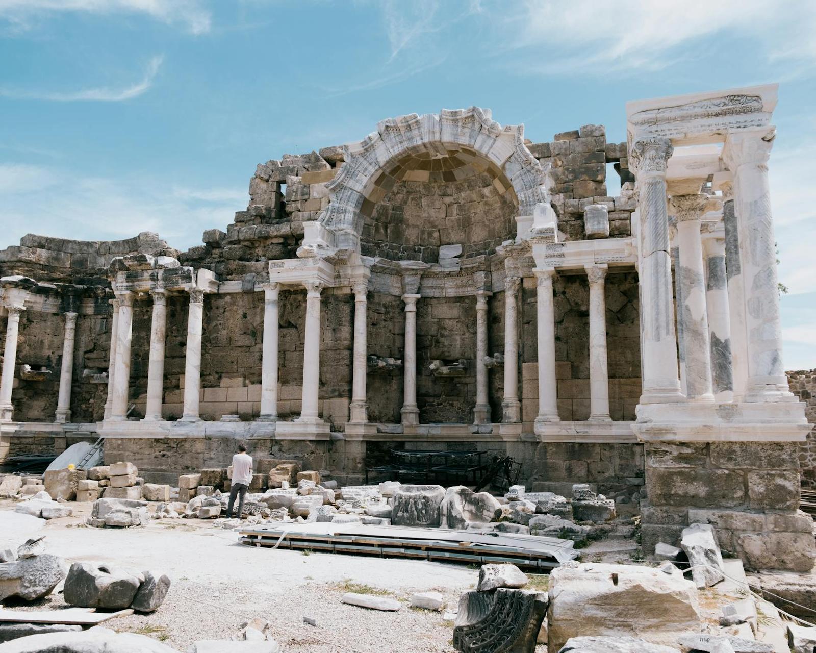 Ancient stone amphitheatre ruins with a colonnaded facade under blue sky