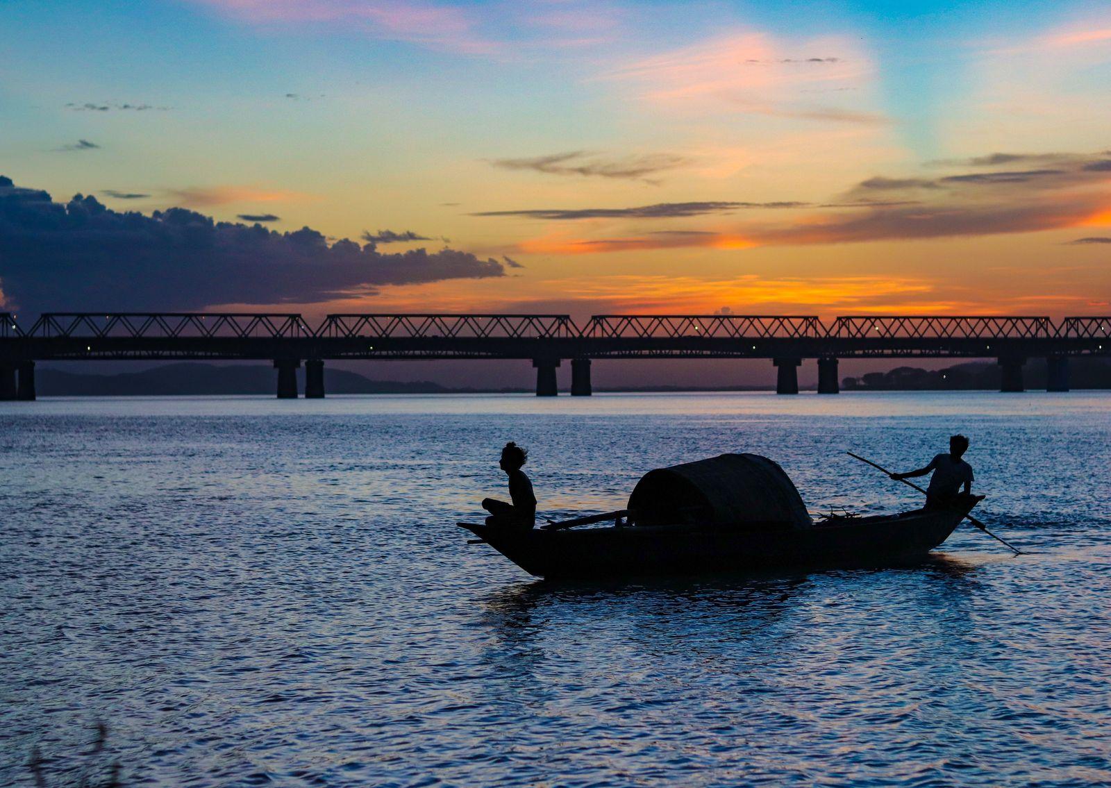 Fishermen on the Brahmaputra at sunset below the Guwahati rail bridge