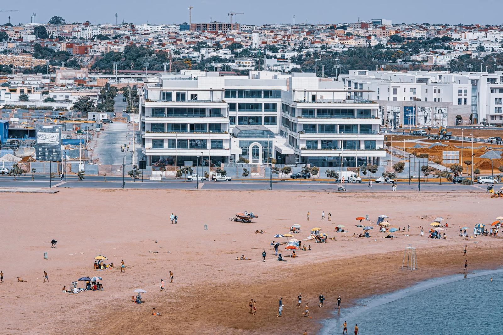 A beachfront hotel overlooking a wide sandy beach dotted with sunbathers