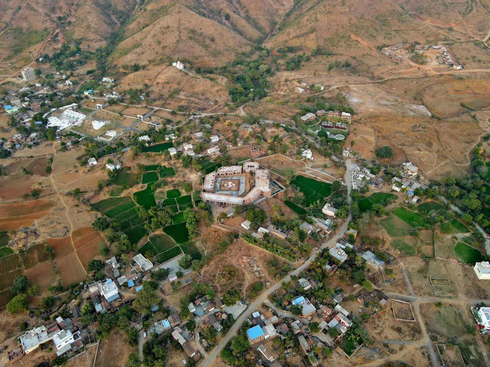An aerial view of a fortified village amid terraced farmland and hills