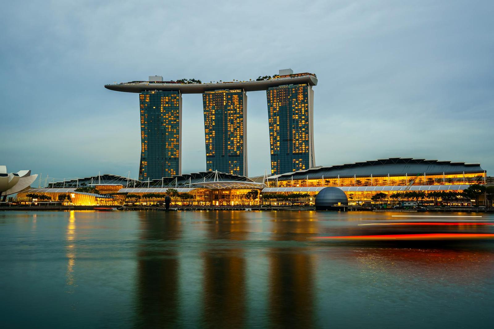 Marina Bay Sands lit up at dusk with a red light trail streaking across the water