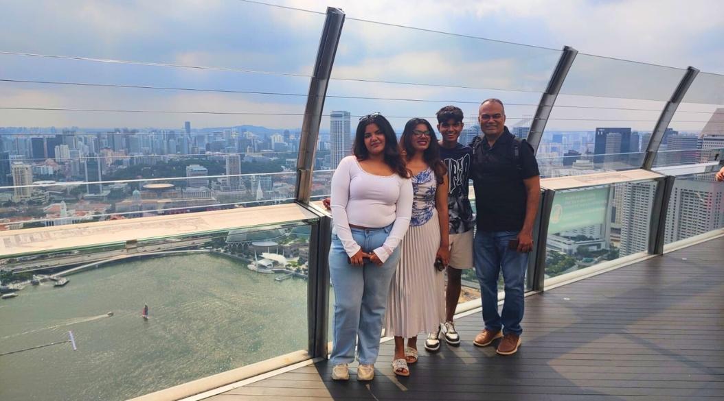Family posing on a high-rise observation deck with city skyline.