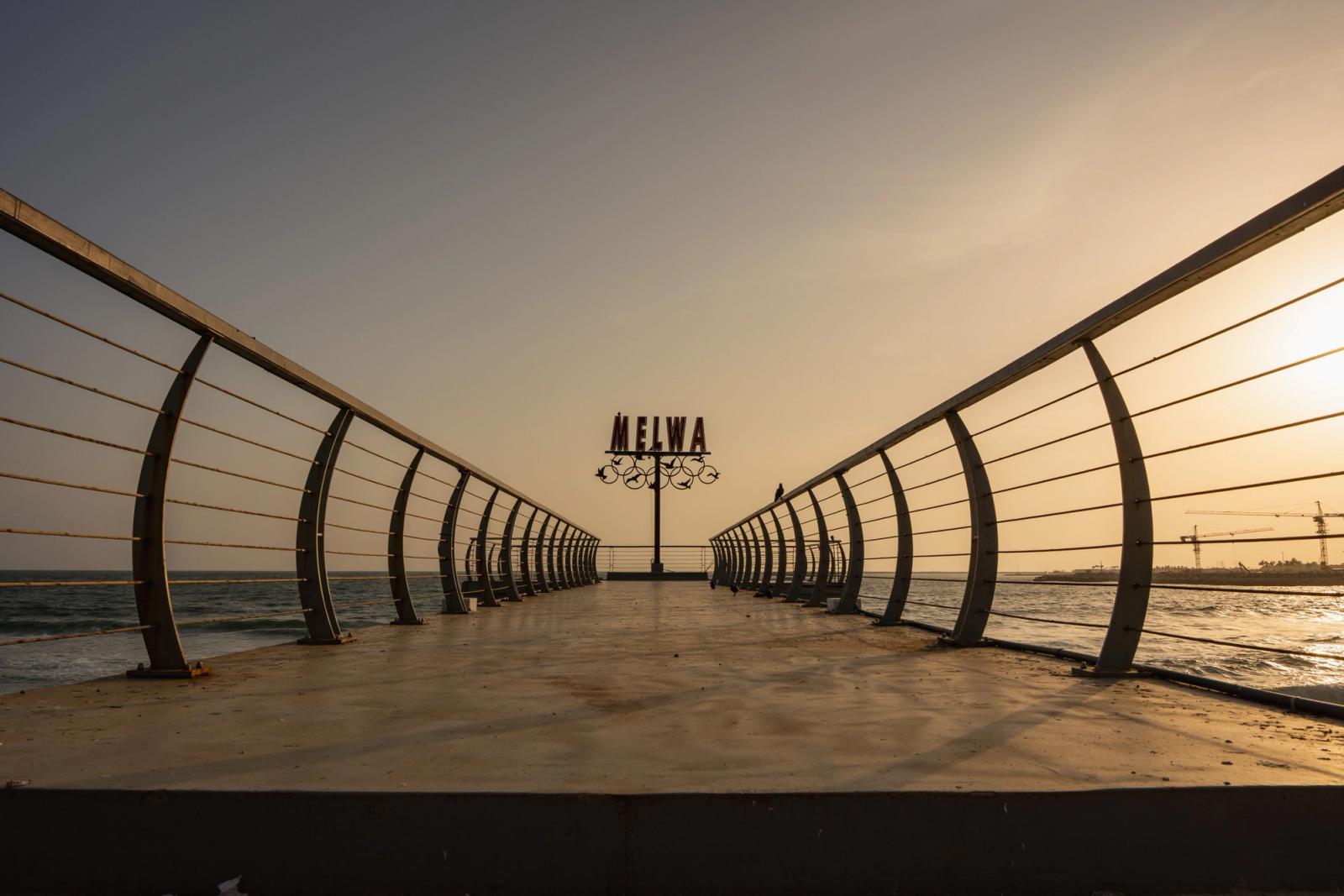 A tranquil scene of a pier extending into the ocean during sunset, captured in Colombo, Sri Lanka