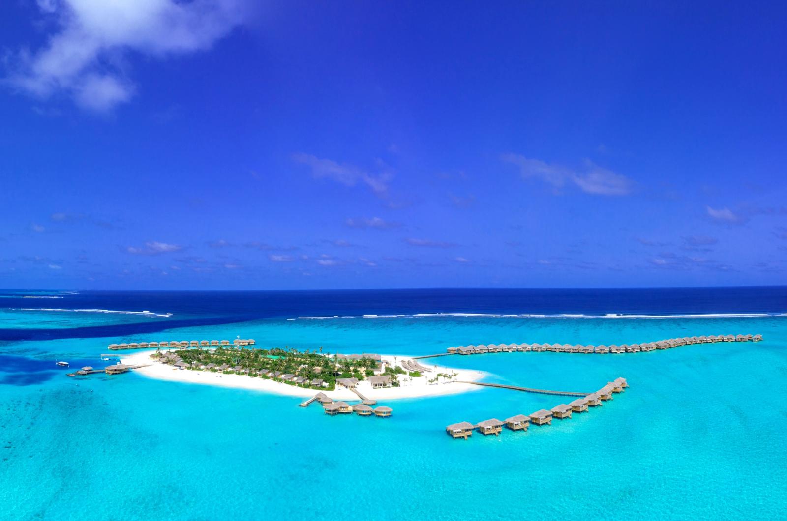 Stunning aerial view of a tropical island resort with overwater villas in the Maldives
