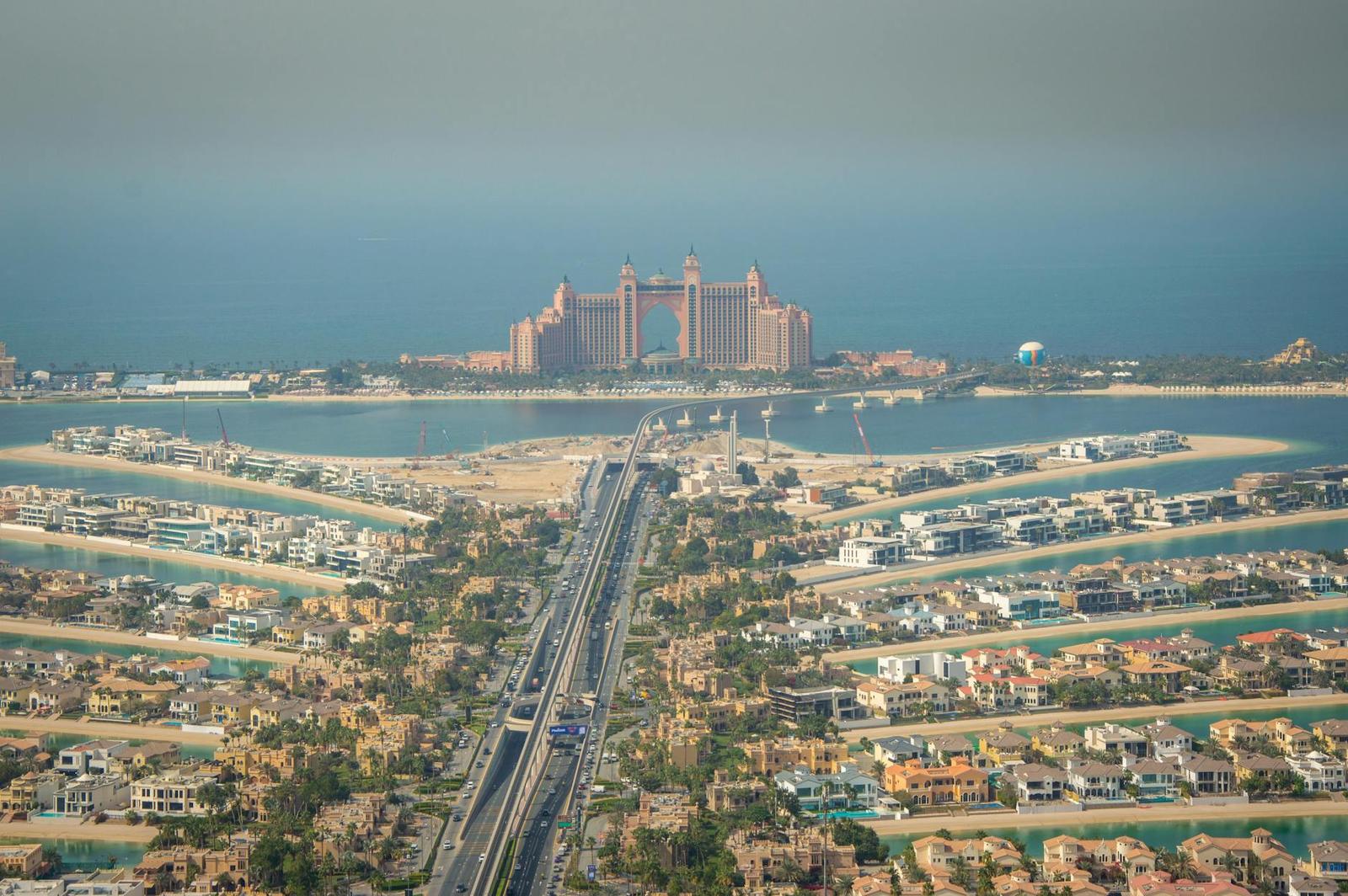 An aerial view of a palm-shaped man-made island with a grand pink resort at its tip