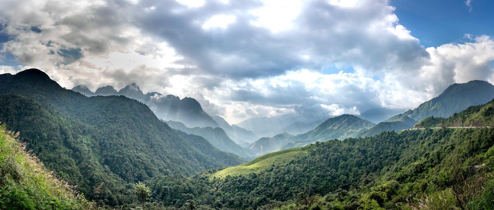 A panoramic mountain valley wrapped in mist with terraced slopes below