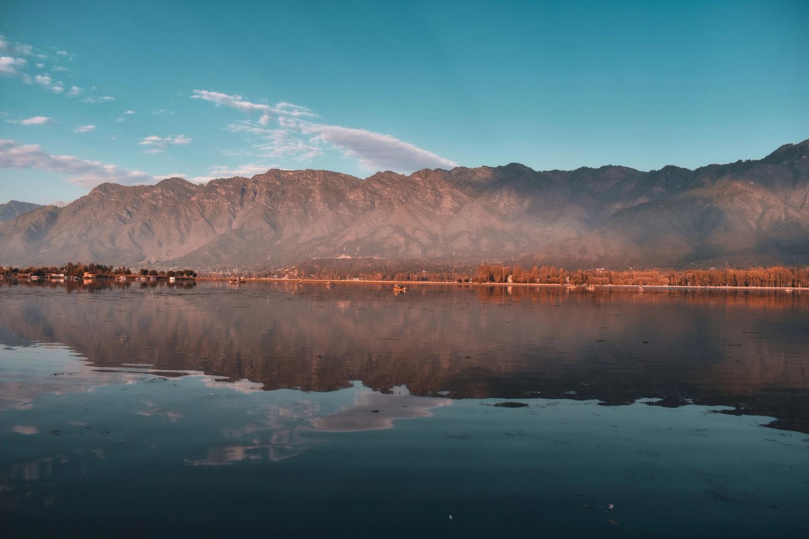 Peaceful scene of Dal Lake with reflections of mountains in Srinagar at sunrise