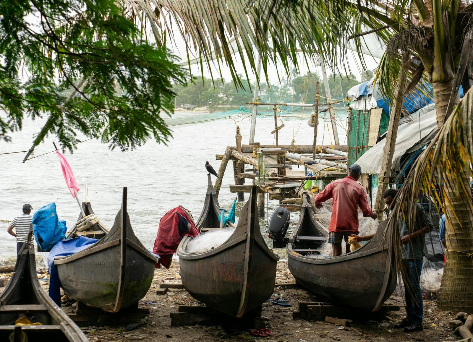 Rustic fishing boats and fishermen on a riverside shore in Cochin, India village