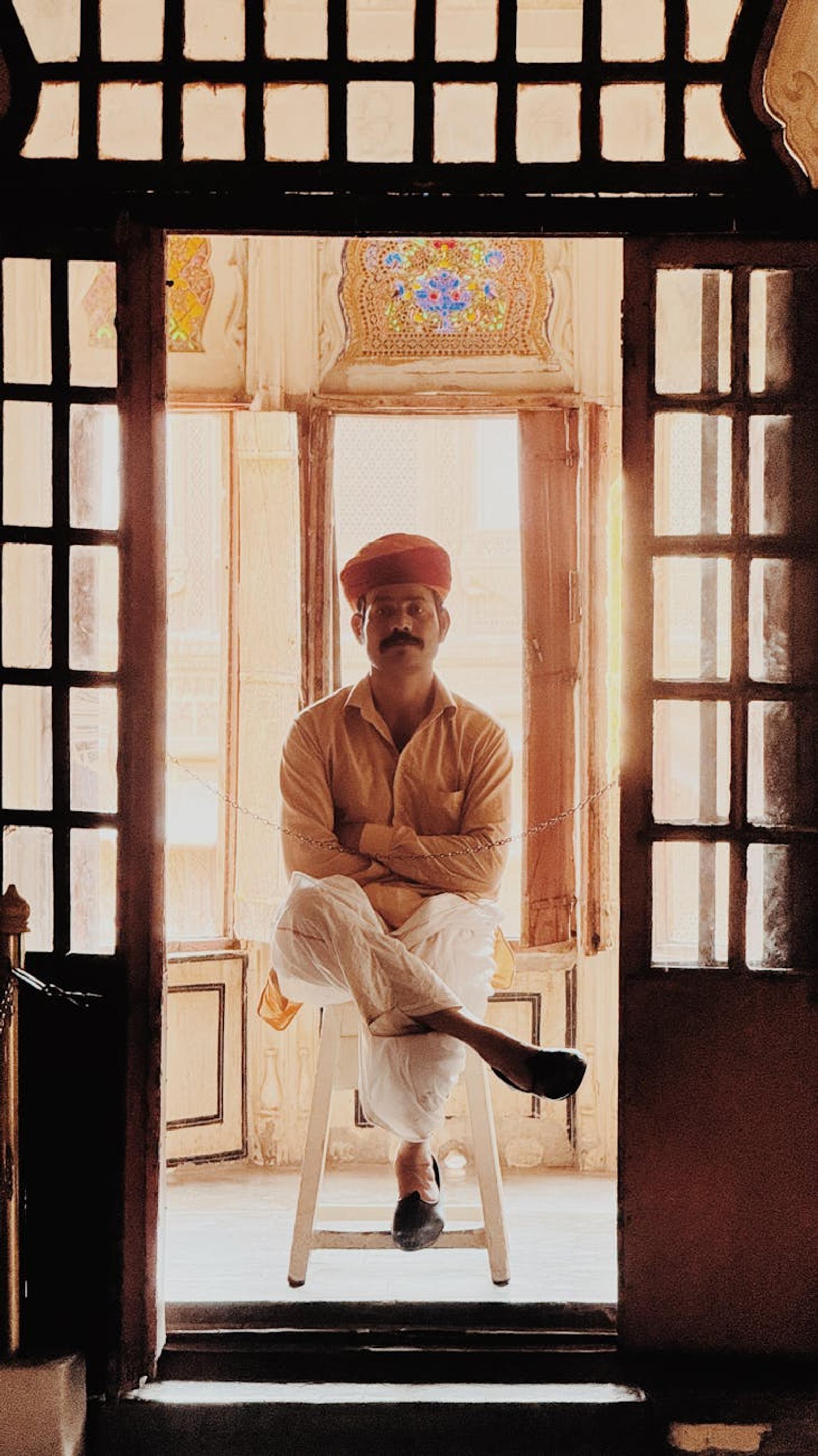 A Rajasthani man wearing traditional attire sits inside a historic building in Jodhpur, India