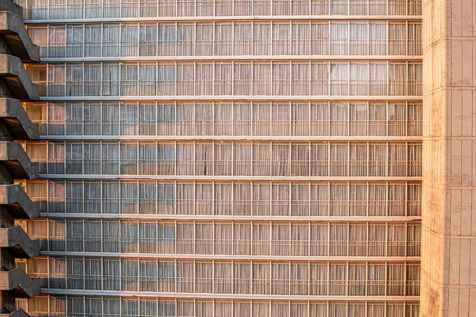 A close-up facade of a high-rise building with rows of stepped balconies at golden hour