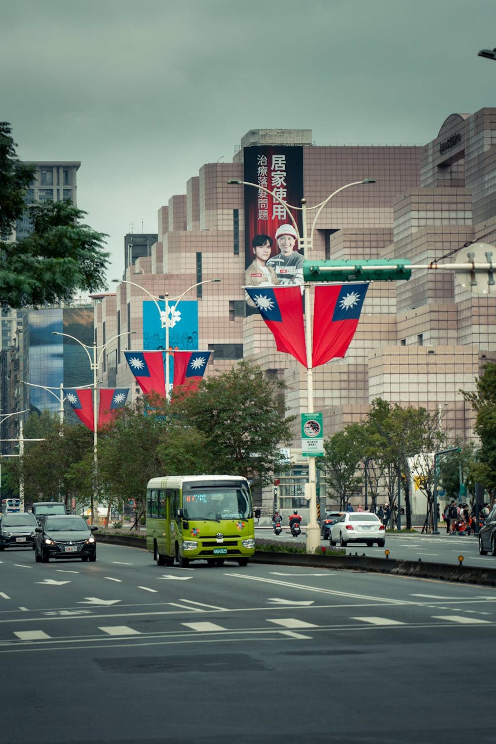 City street hung with large flags beside a billboard-covered building